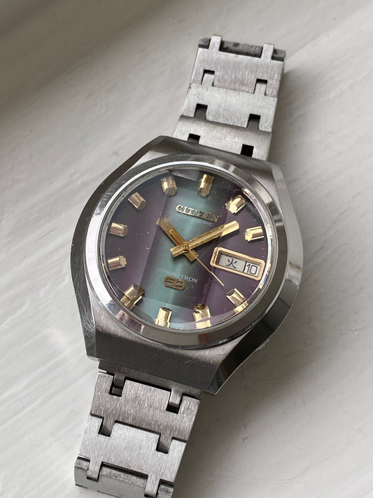 Vintage Citizen Cosmotron watch with purple and turquoise dial and day/date feature, stainless steel bracelet and 7802 movement, tilted front view